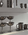 Minimalism stainless steel ice cream cups on shelf, alongside other sleek metal kitchenware, showcasing elegant design and sophistication.
