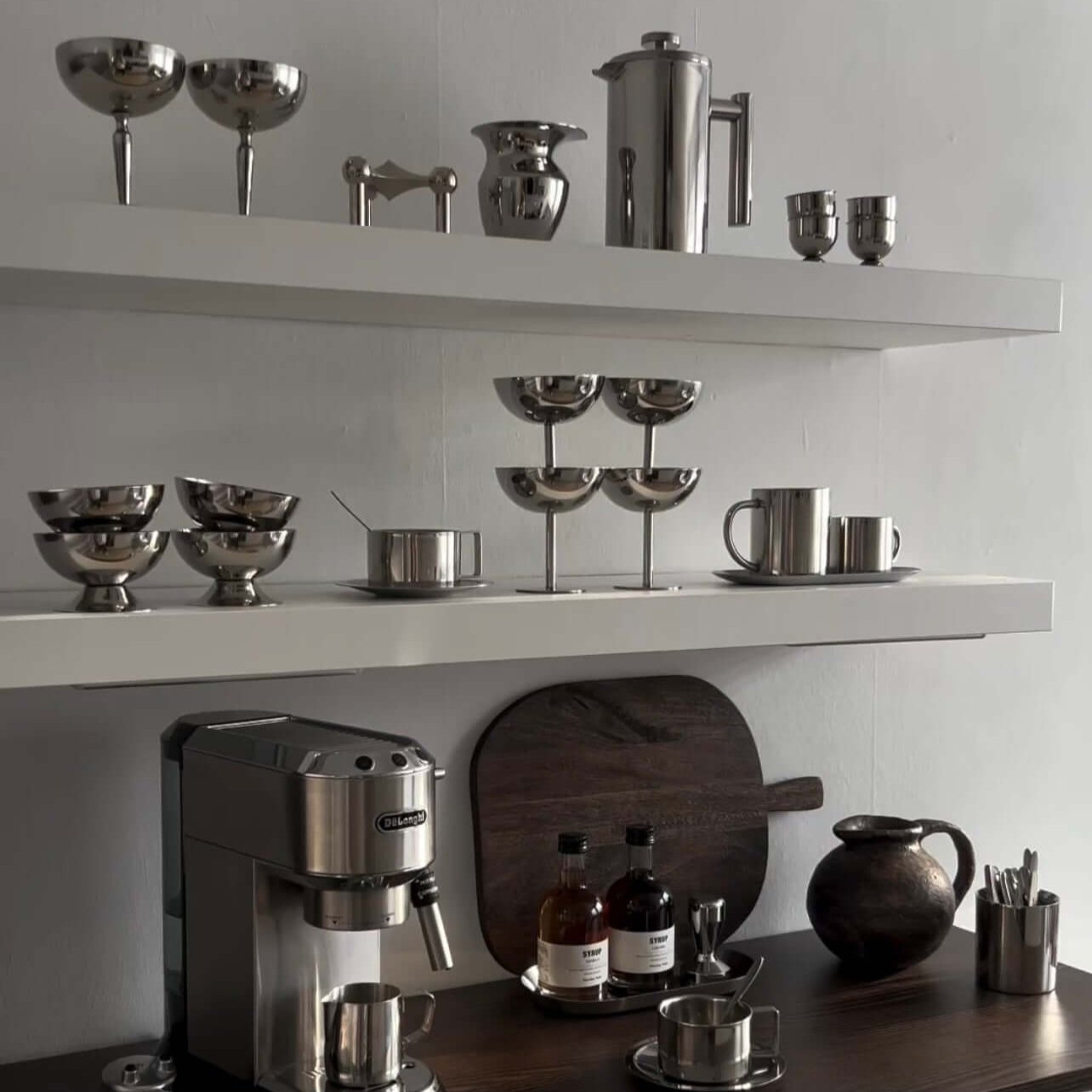Modern kitchen with stainless steel ice cream cups and kitchenware on shelves.