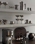 Modern kitchen with stainless steel ice cream cups and kitchenware on shelves.