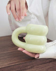 Unique green ceramic mug with a sculpted, modern design, held by a person on a wooden table.