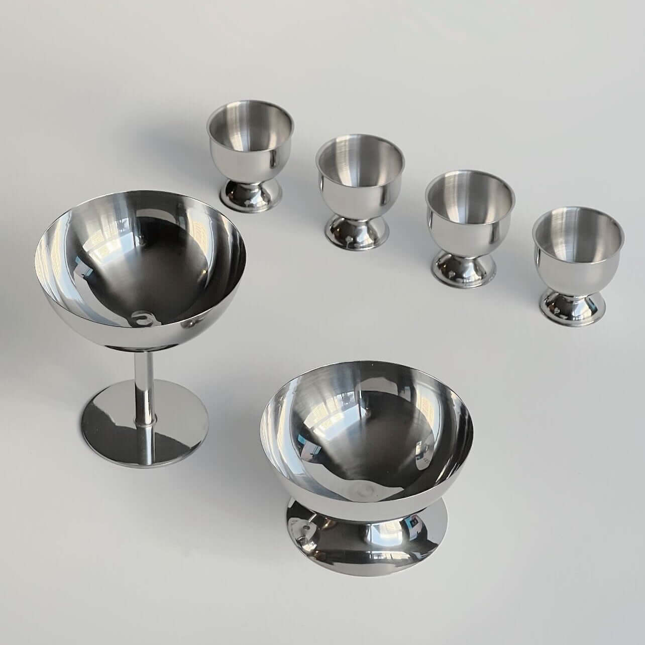 Stainless steel egg holders set of six with an elegant matte finish, perfect for kitchen decor and family breakfasts.