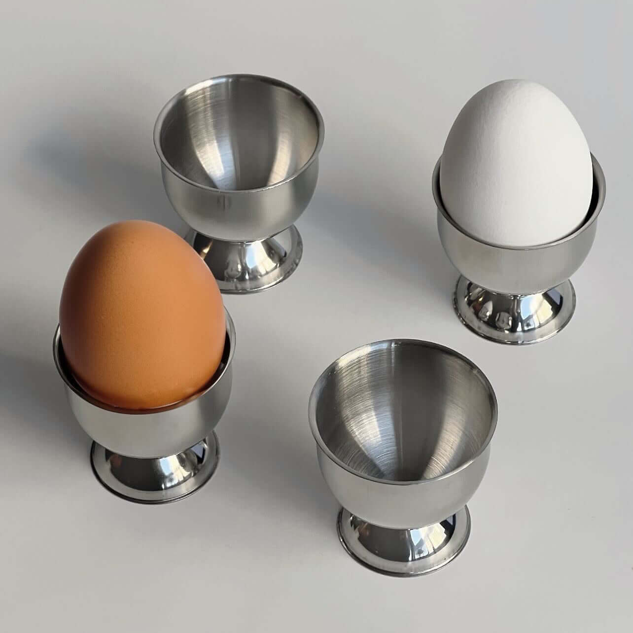 Stainless steel egg holder set of 4 with a matte finish, ideal for stylish kitchen decor and family breakfasts.