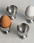 Stainless steel egg holder set of 4 with a matte finish, ideal for stylish kitchen decor and family breakfasts.