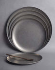 Set of matte-finish stainless steel Hakone Plates stacked with a wooden fork, perfect for elegant dining.