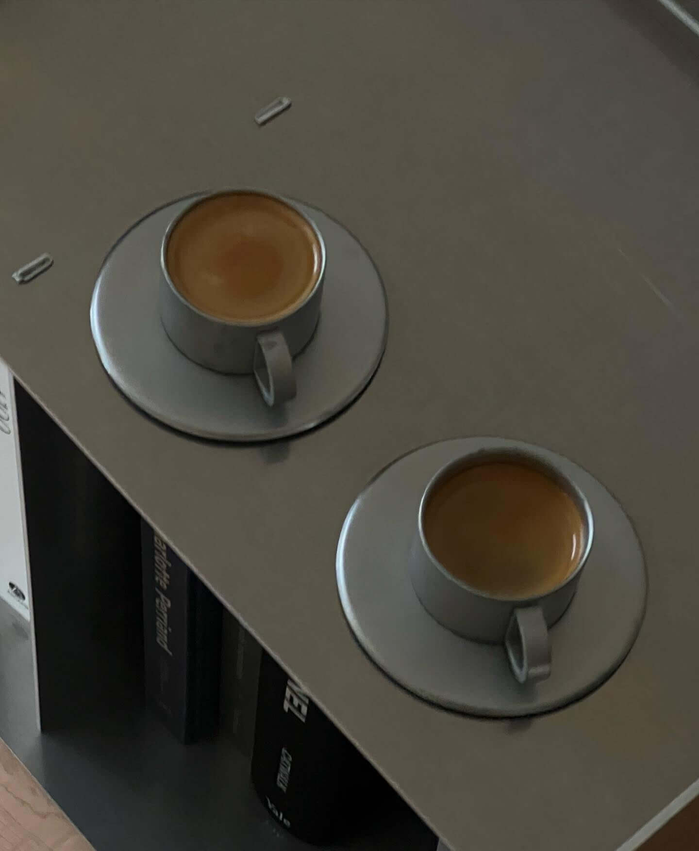 Two VINTAGE INOX stainless steel cups and saucers with espresso, chic design, on a grey tabletop.
