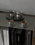 Vintage INOX stainless steel cup and saucer set with teapot and creamer on a shelf with books.