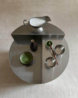 Modern tea set with stainless steel pitcher and bowls on a sleek circular table showcasing stylish design and functionality.