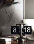Stylish turning desktop clock with a page-turning mechanism, ideal for Japanese or Nordic-inspired interiors, on a wooden desk.