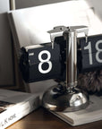 Sleek turning desktop clock with page-turning mechanism, blending Japanese and Nordic aesthetics on a minimalist desk.