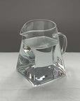 Aeris Frosted Glass Pitcher with water, angular base and curved spout
