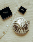 Vintage Metal Shell Box closed on a cream knitted cardigan