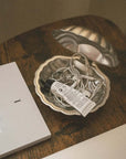 Vintage Metal Shell Box open on a wooden table with a glass shell dish inside