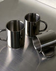 Double-layer glossy stainless steel cups on metallic surface, modern elegance, perfect for temperature control and any occasion.