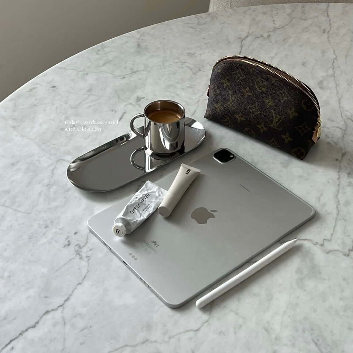 sleek workspace with tablet, stylus, coffee on steel tray, luxury pouch on marble table.