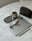 sleek workspace with tablet, stylus, coffee on steel tray, luxury pouch on marble table.