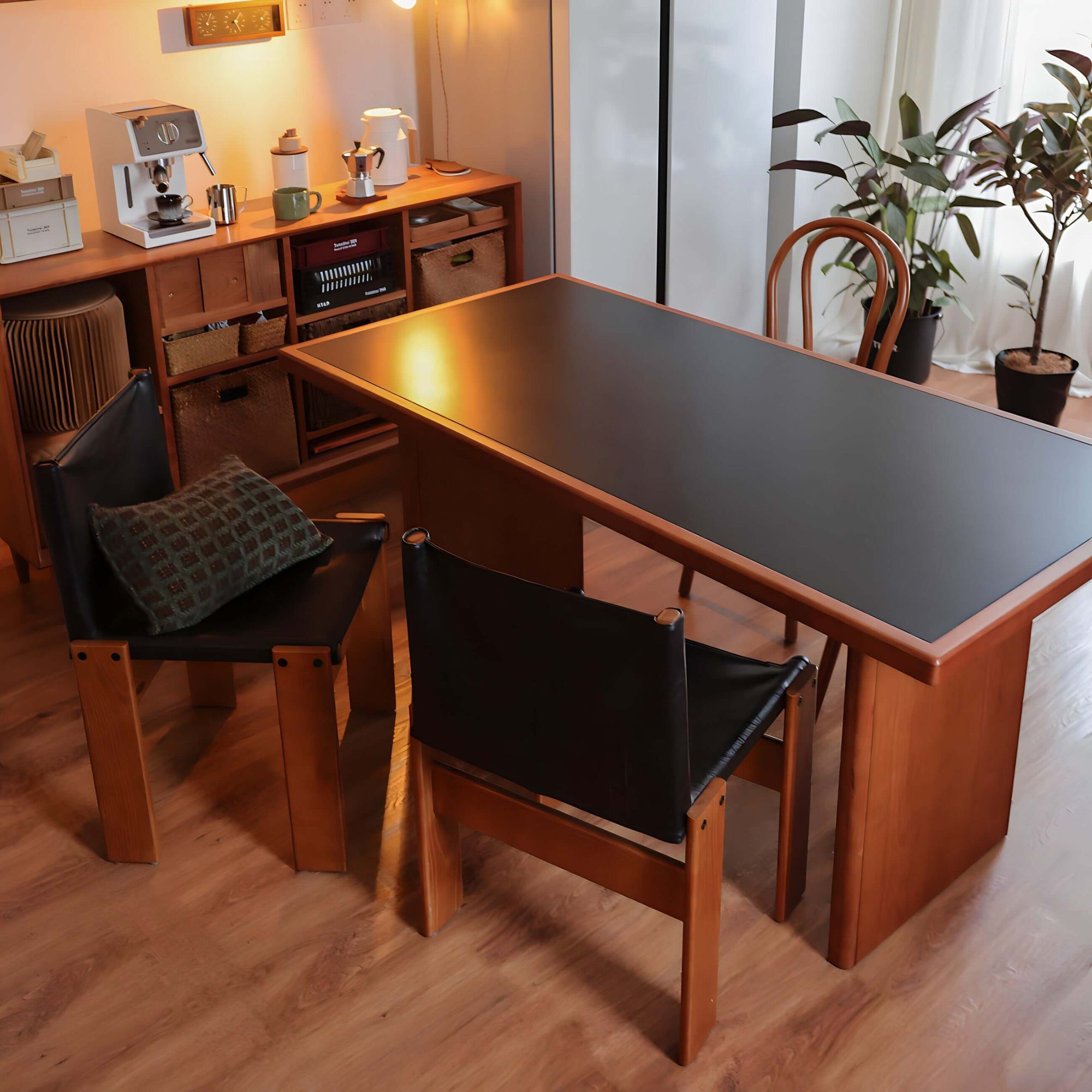 Cherry wood Gora dining table with black leather Nosaku monk chairs in cozy room setting.