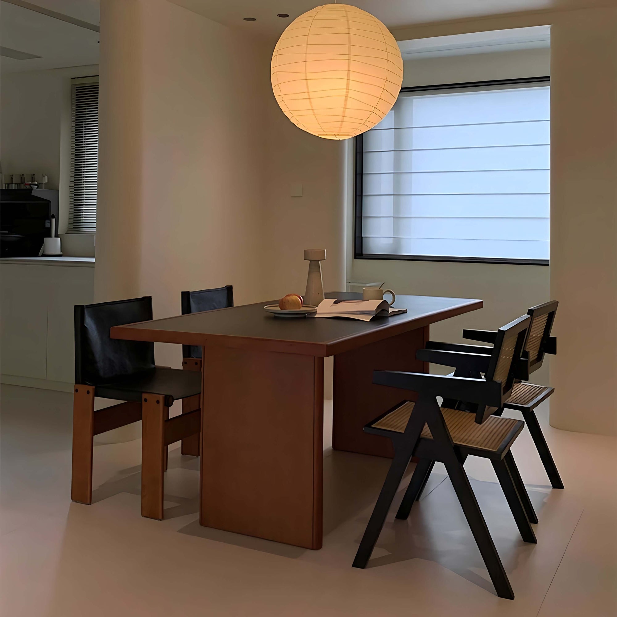 Modern dining room with Gora cherry wood table, black Nosaku Monk chairs, and a hanging round paper lantern.