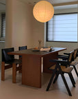 Modern dining room with Gora cherry wood table, black Nosaku Monk chairs, and a hanging round paper lantern.