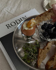 Noir Steel Plate with a boiled egg, berries and bread on a magazine