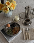 Breakfast on Noir Steel Plates with a French press and yellow flowers