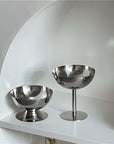 Minimalist stainless steel ice cream cups elegantly displayed on a white shelf, showcasing modern design and sophistication.