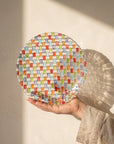 Tessera hand-painted mosaic plate 28.2 cm held against a sunlit ivory wall