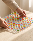 Hands placing the Tessera square platter on a stone table