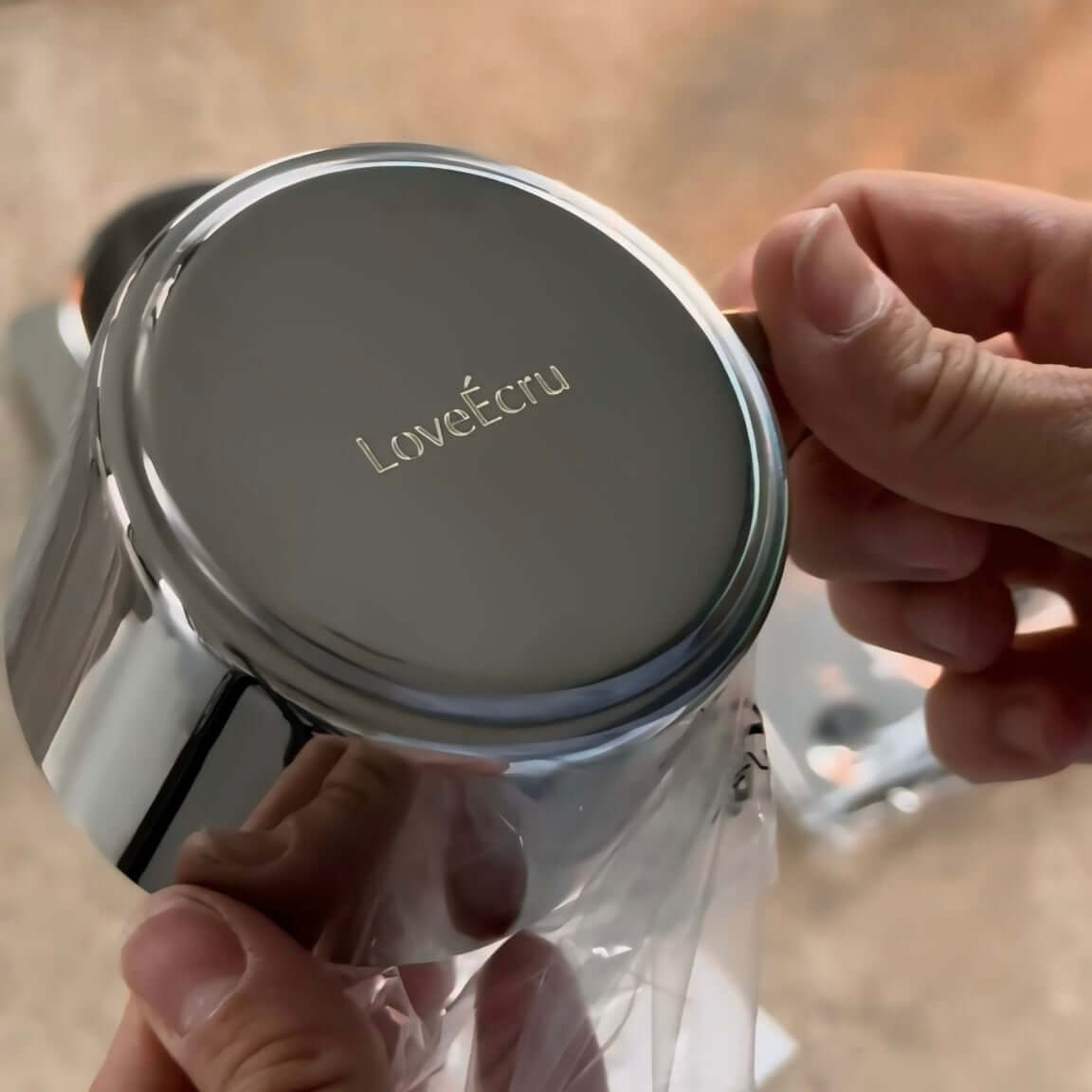 Hands holding Venice Mirror Cup with engraved logo, showcasing polished mirror finish and luxury design.