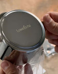 Hands holding Venice Mirror Cup with engraved logo, showcasing polished mirror finish and luxury design.