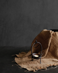 Antique Aimu table candle holder with distressed details on brown fabric, adding vintage charm to home decor.
