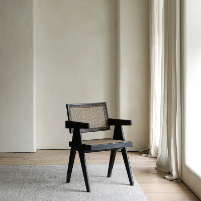 Chandigarh chair made of African teak and rattan, featuring wabi-sabi design and Buddha-inspired carvings in a minimalist setting.
