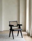 Chandigarh chair made of African teak and rattan, featuring wabi-sabi design and Buddha-inspired carvings in a minimalist setting.