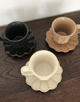 Rinka Mug & Plate Set in black, brown, and cream colors displayed on a wooden surface