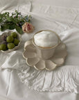 Elegant Rinka Mug with frothy coffee on a flower-shaped porcelain saucer from Kaneko Kohyo, styled with roses and fruit.