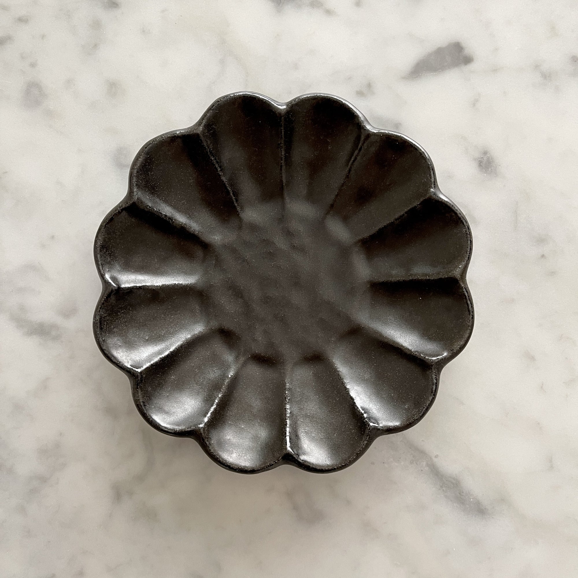 Rinka Plate 14cm black porcelain with floral design, handcrafted in Japan, elegant and microwave safe, on a marble background.