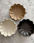 Three Rinka Collection bowls by Kaneko Kohyo in brown, white, and black porcelain on a marble surface.
