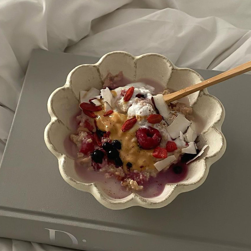Rinka Bowl 16cm filled with oatmeal, topped with berries, and coconut flakes on a book, part of Kaneko Kohyo's Rinka Collection from Japan.