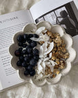 Rinka porcelain bowl with blueberries, coconut flakes, and granola on an open book background.