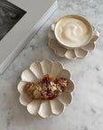 Rinka porcelain plates with dessert and coffee on marble table, part of Kaneko Kohyo's handcrafted flower-shaped tableware collection.