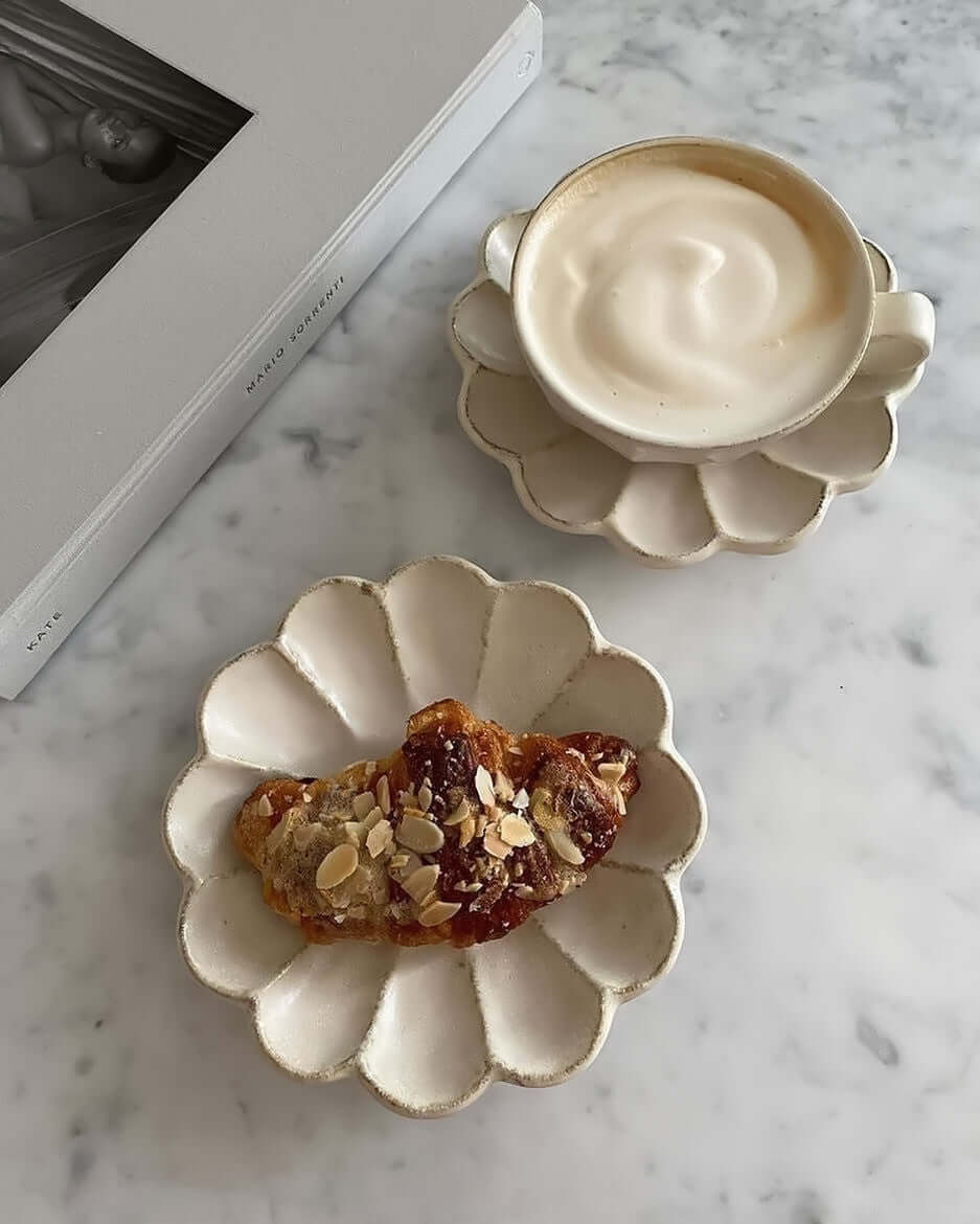 Rinka soup cup with foam and flower-shaped plate with pastry on marble table, showcasing Kaneko Kohyo's handcrafted porcelain design.