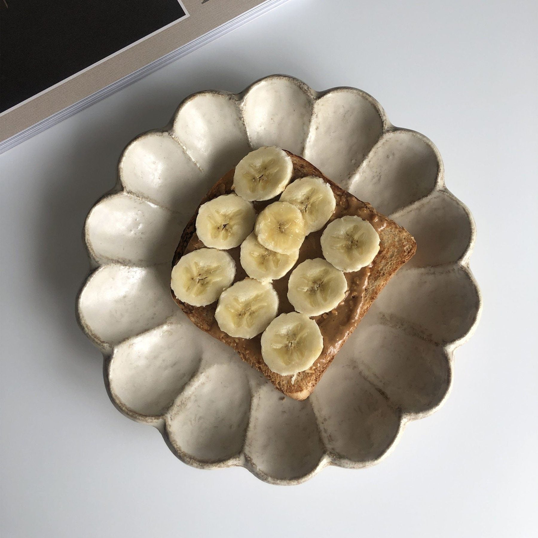 Flower-shaped porcelain plate with banana and peanut butter toast