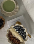 Ceramic Rinka Bowls with green tea and granola breakfast topped with blueberries and coconut, lifestyle book in background