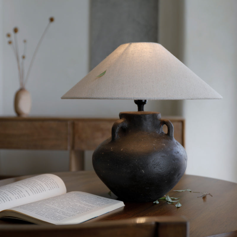 Handmade Ear Table Lamp with pottery body on wooden table, soft light ambiance, open book nearby.