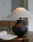 Handmade Ear Table Lamp with pottery body on wooden table, soft light ambiance, open book nearby.