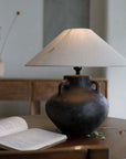 Handmade Ear Table Lamp with pottery body on wooden table, soft light ambiance, open book nearby.