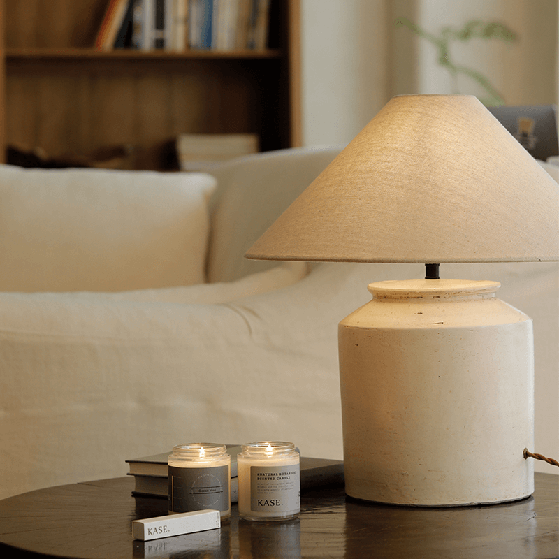 Linen folding shoulder table lamp on coffee table with candles, offering warm, adjustable lighting and vintage decor in cozy living room setting.