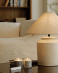 Linen folding shoulder table lamp on coffee table with candles, offering warm, adjustable lighting and vintage decor in cozy living room setting.