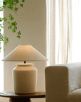 Folding Shoulder Table Lamp with linen shade on wood table beside sofa, adds warm light and decor to room. Adjustable dimming switch.