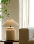 Folding Shoulder Table Lamp with linen shade on wood table beside sofa, adds warm light and decor to room. Adjustable dimming switch.