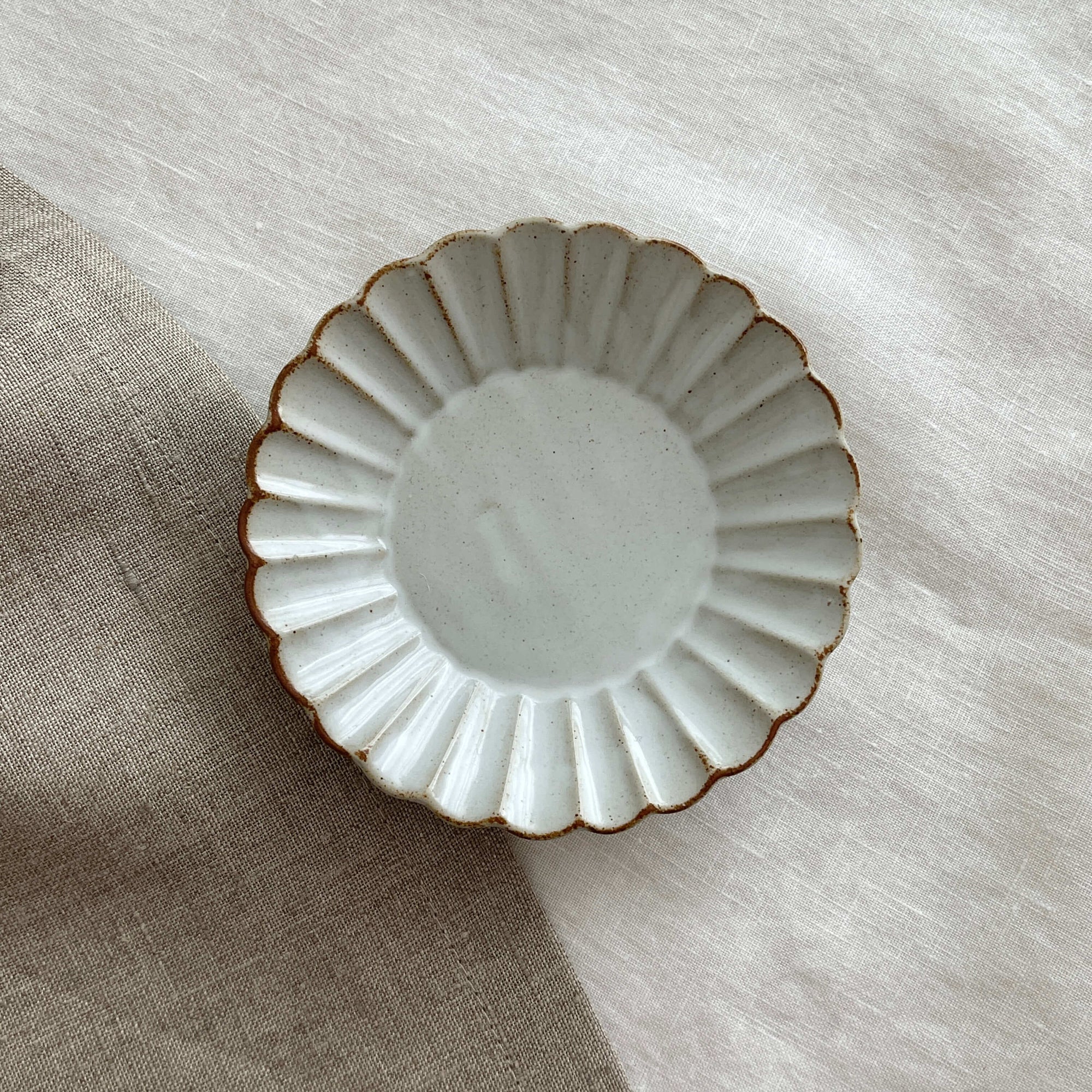 Marumitsu Barbarie plate with petal-like rim on linen background, showcasing elegant design and pottery craftsmanship.
